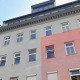 Anlegerwohnung im 10. Bezirk, Wohnhaus mit grau-rosa Fassade, Fenster weiß, Dachausbau