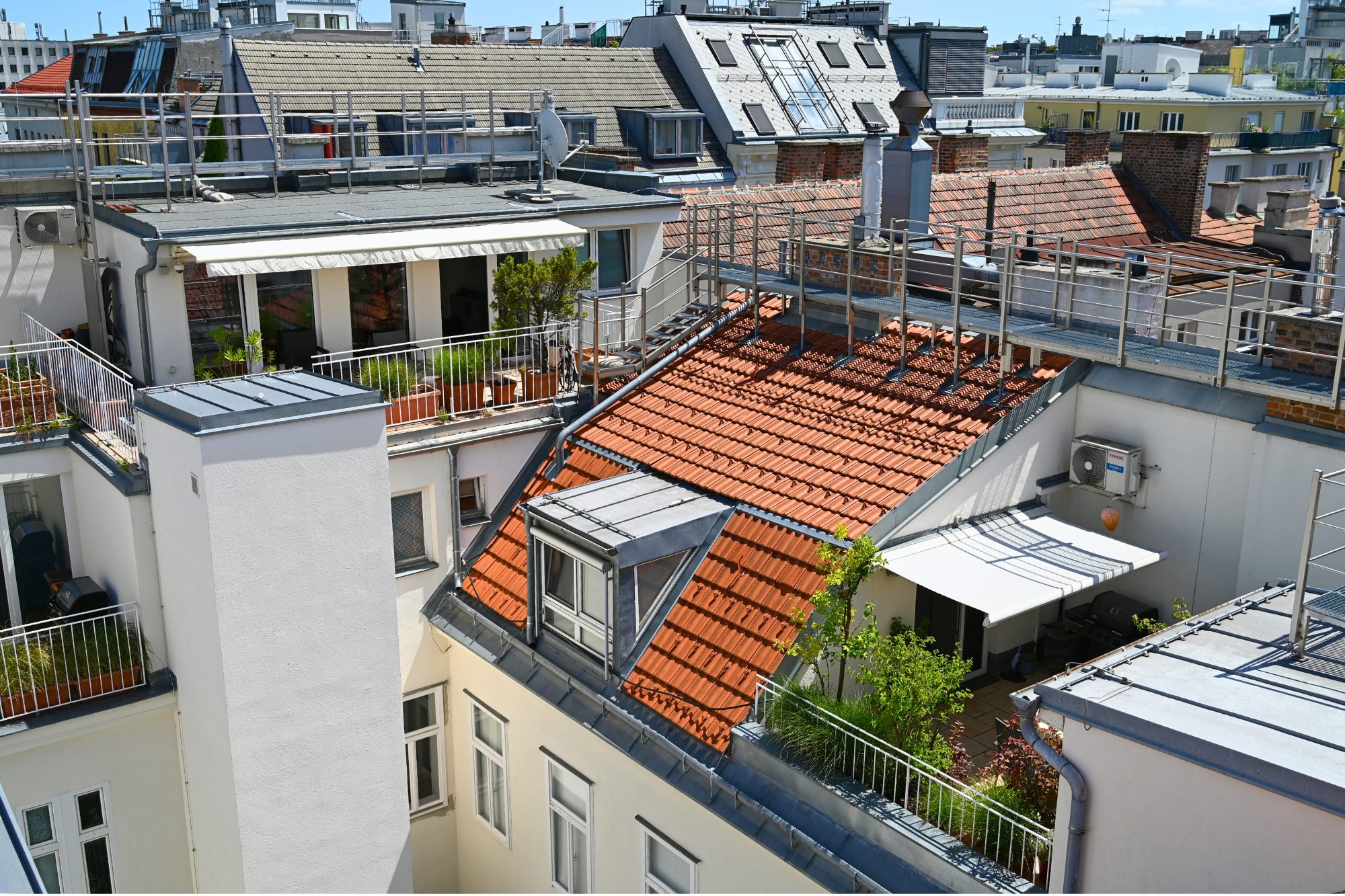 Dachterrassenwohnung im 8. Bezirk von Wien, Blick auf zwei Terrassen, möbliert und begrünt, mit Markisen, Blick über die Dächer, Dach im Vordergrund rot, mit Gaupe