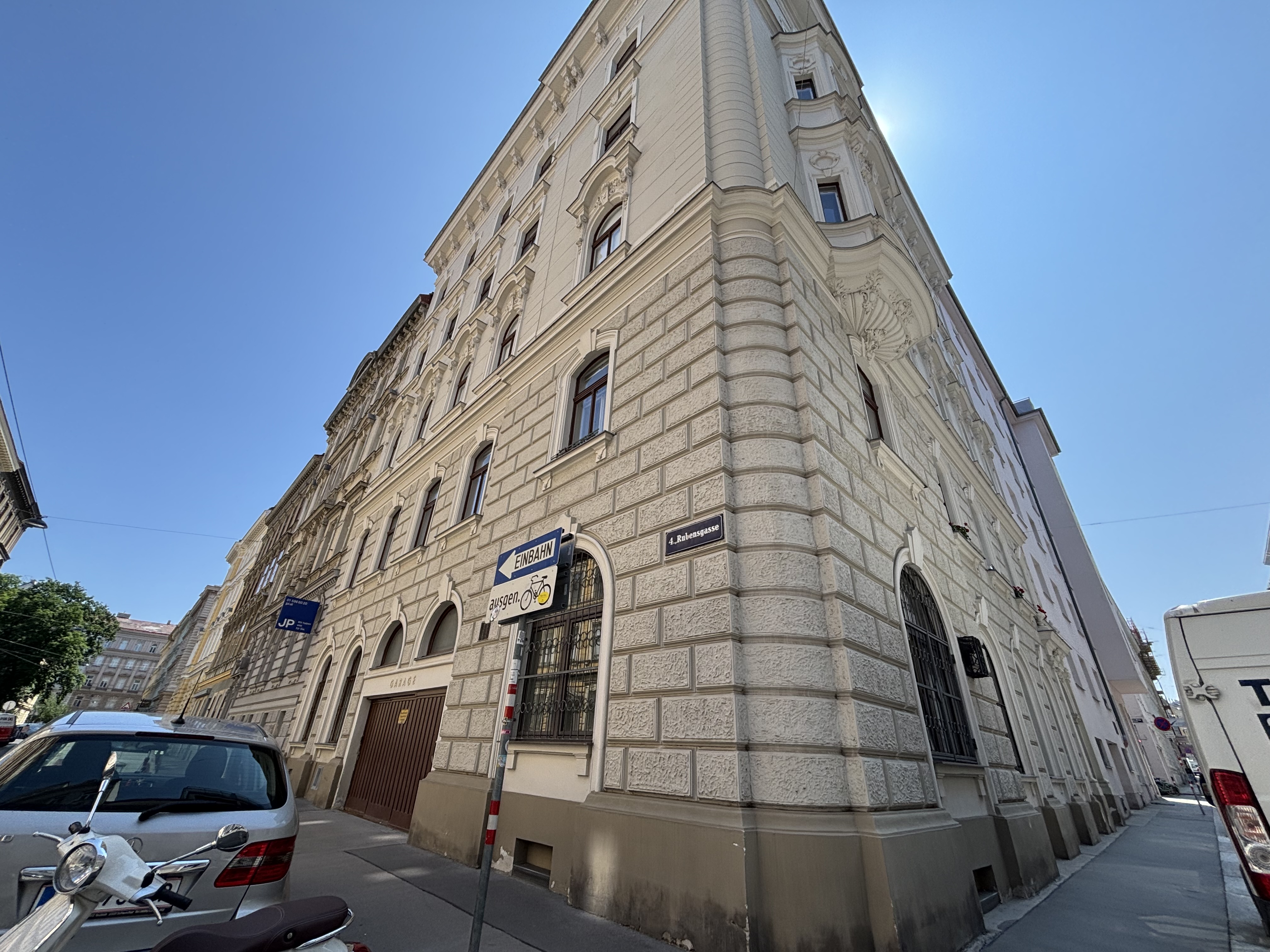 4. Bezirk von Wien, Altbau-Eckzinshaus, beige-graue Fassade, dunkelbraune Fenster, Gehsteig links und rechts,