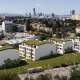 Wohnhausanlage im 22. Bezirk von Wien, mit mehreren Gebäudekomplexen, Dächer begrünt, weiße Fassade, Bahnlgleise davor, Blick über Wien