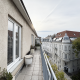 Ausblick von einer Dachgeschosswohnung in Wien Hietzing, graue Fassade, weiße Fenster, lange schmale Terrasse, Baum und schöne Altbauten vis a vis