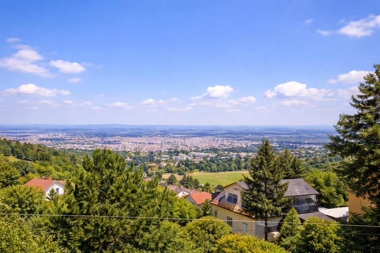 Baugrundstück im 18. Bezirk von Wien, Ausblick über die Stadt, im Vordergrund Bäume, Sträucher und Häuser