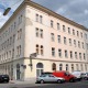 Außenansicht eines mehrstöckigen Wohnhauses im 11. Bezirk Wiens, Eckhaus, weiße Fenster, helle Fassade, parkende Autos davor