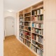 Blick in einen Eingangsbereich einer Wohnung im 2. Bezirk von Wien, Parkettboden, weiße Wände, rechts Wandverbau mit Bücherregal aus hellem Holz
