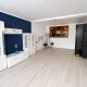 großer Wohnraum, mit weißen Möbeln, eine Wand in dunkelblau, Decke weiß, heller Boden