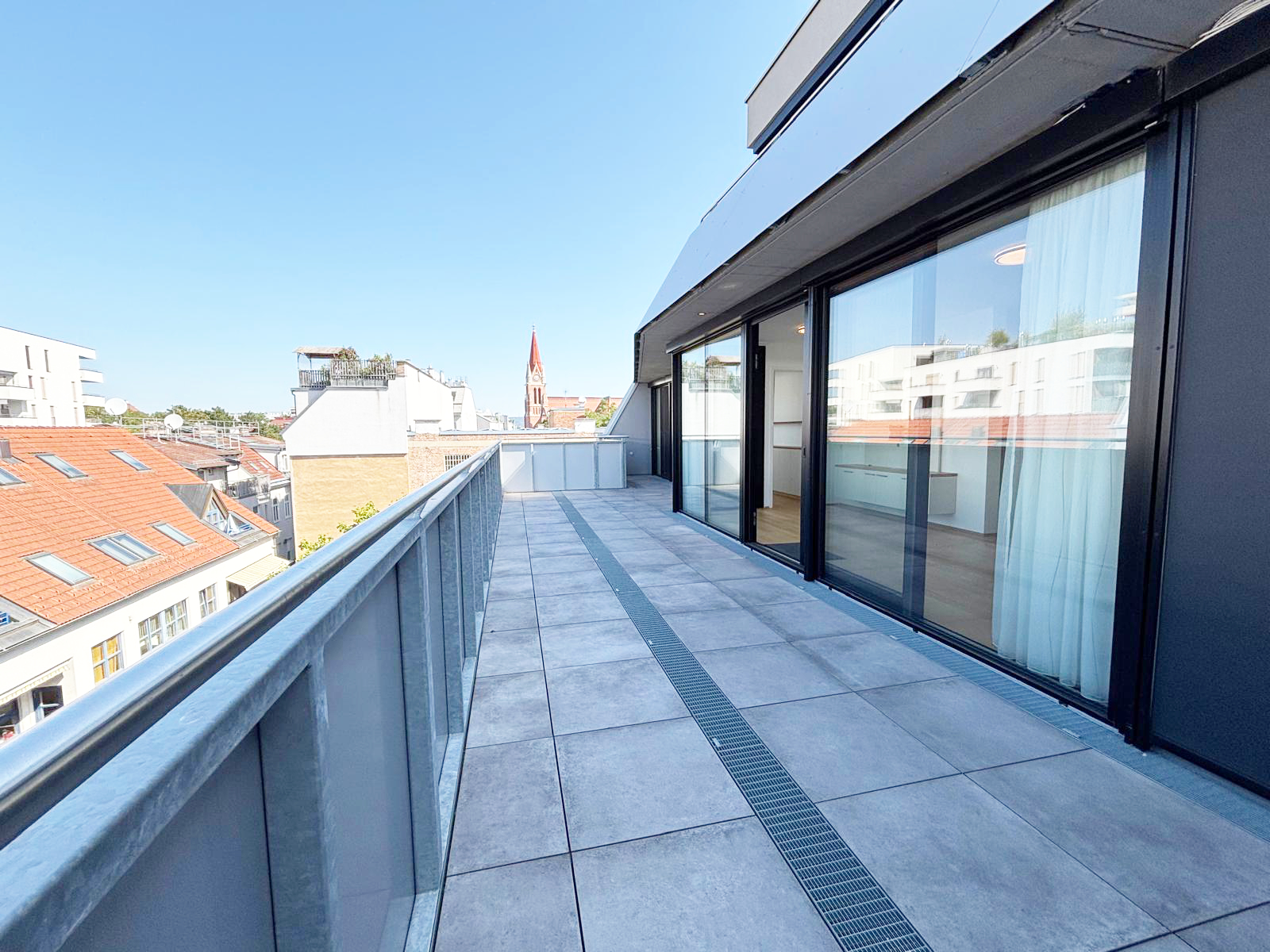 großzügiger Terrassenbereich einer DG-Wohnung im 14. Bezirk von Wien, großflächige Terrassentüren, modernes Ambiente