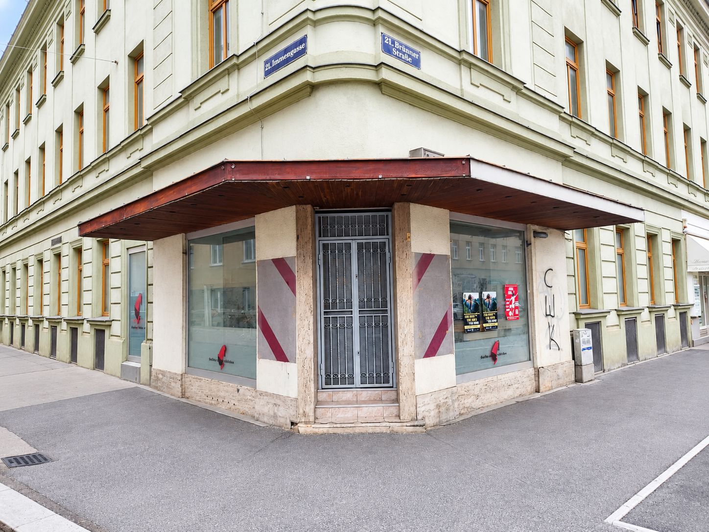 Eck-Geschäftslokal im 21. Bezirk von Wien, mittig eine vergitterte Einganstür, links und rechts davon eine Glasfront, davor ein Gehsteig